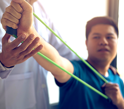 Young patient uses green resistance band with instruction from his physical therapist