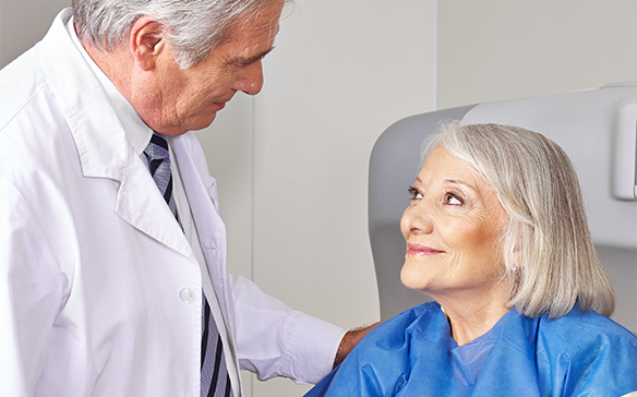 An older male doctor reassures a female senior patient about her open MRI procedure.