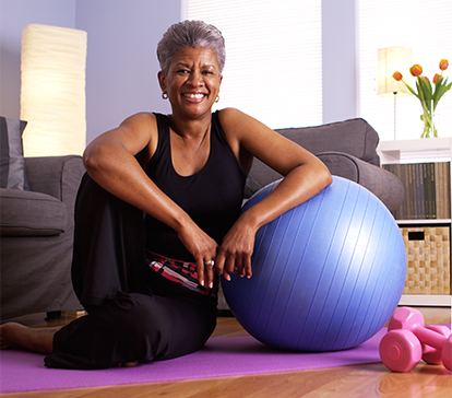 African American lady with total hip replacement exercises at home with purple exercise ball